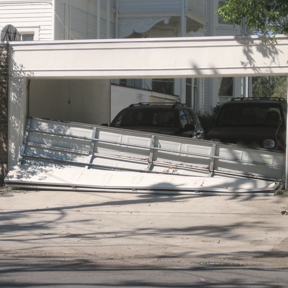 A garage door knocked off its tracks and hanging out of the opening